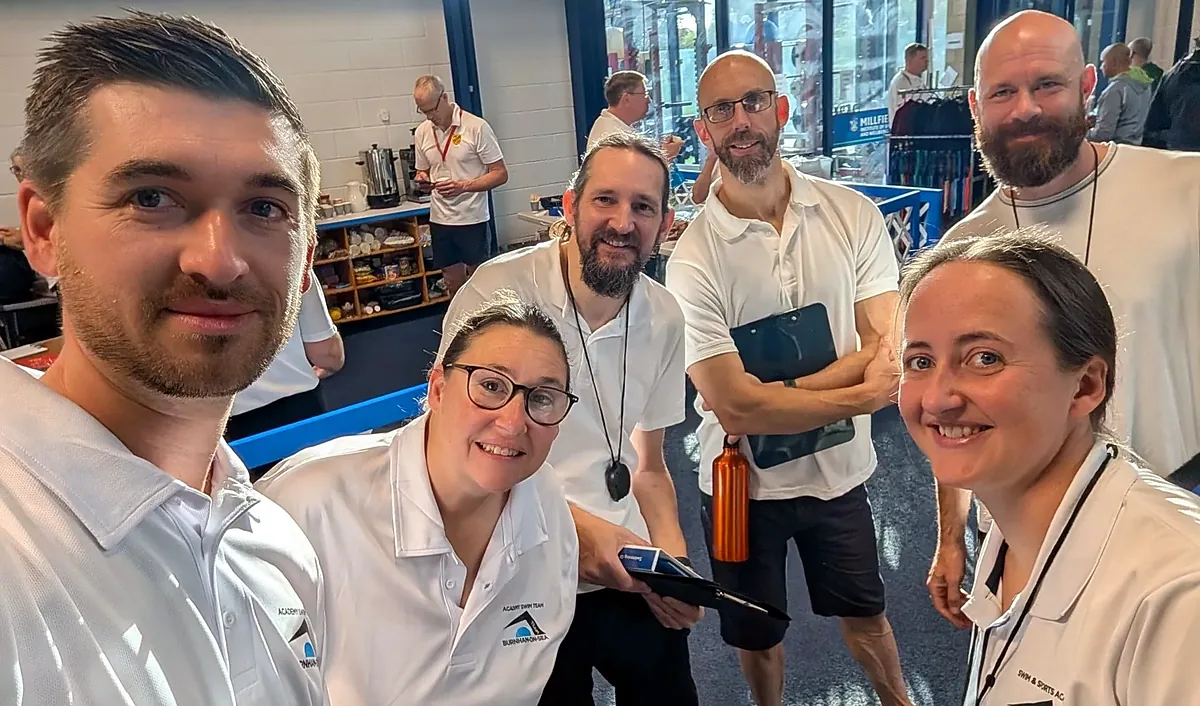 Six Academy Swim Team volunteers in white club polo shirts smiling together at a gala